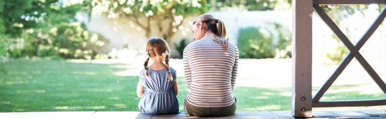Christian discipline - mother and child seated on porch steps, facing the backyard grass and trees